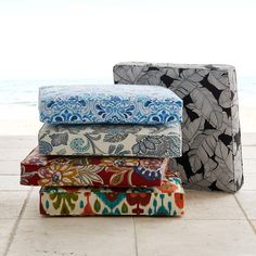 four pieces of fabric stacked on top of each other in front of the ocean and sky