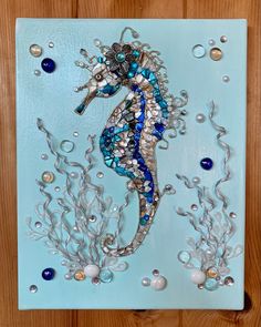 a sea horse made out of glass and beads on a blue background with wood planks