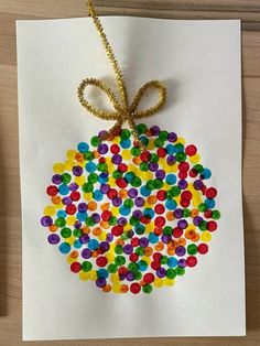 an ornament made out of colored candies on paper with a gold ribbon