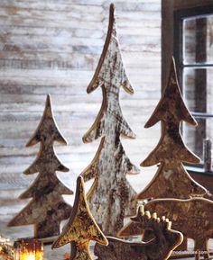 three wooden christmas trees sitting next to each other on top of a table with candles in front of them