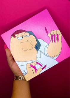 a hand holding up a pink card with a cartoon character on it