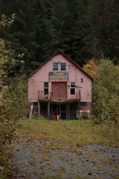 an old red barn sits in the woods