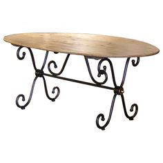 an oval wooden table with wrought iron legs