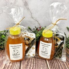 two bottles of honey sitting on top of a wooden table