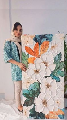 a woman standing next to a painting with flowers on it