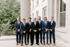 a group of men in suits standing next to each other on a sidewalk with trees in the background