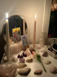 a table topped with rocks and candles next to a mirror on top of a table