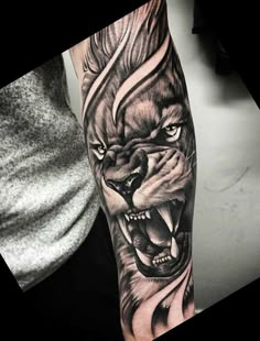 a man's arm with a black and grey tattoo of a lion on it