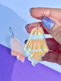 a hand holding a plastic ghost ornament in front of a purple and blue background