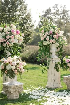 three white vases with flowers on them sitting in the grass