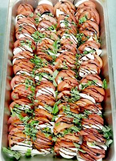 a tray filled with lots of sandwiches covered in toppings on top of each other