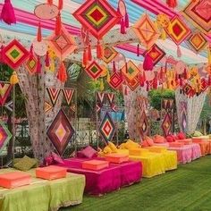 many colorful decorations are hanging from the ceiling in an outdoor event area with green grass