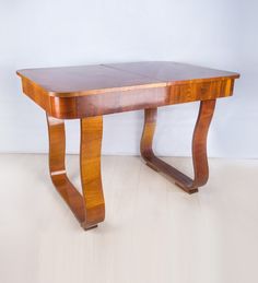 a wooden table sitting on top of a hard wood floor next to a white wall