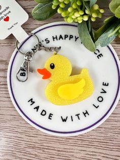 a rubber ducky keychain is sitting on a plate next to some flowers