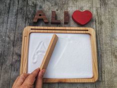 "Montessori believed that \"what the hand does, the mind remembers\". So, a Wooden sand tray will help your child easily internalize the letters:) The Waldorf learning resource educating your littles on their learning, fine motor skills, hand eye coordination.  A simple tray for sand, salt  or small grains so that your baby can recognize the first letters with a finger. They use sand tray for tracing numbers, shapes, letters, and words. I designed this sand tray with one large section on top for Waldorf Learning, Sand Writing, Waldorf Dolls Clothes, Waldorf Montessori, Sand Tray, Wooden Pencil, Alphabet Writing, Wooden Alphabet, Homeschool Learning