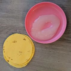 two yellow and pink plates sitting next to each other on a wooden table, one with food in it