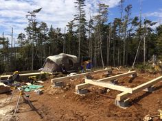 a tent is set up in the middle of a forest with benches and construction equipment around it