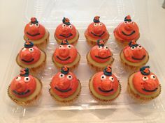 cupcakes with orange frosting decorated as faces and eyes are in a plastic container