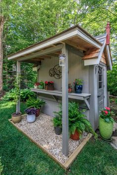 an outdoor garden shed with potted plants on the outside and in the front yard