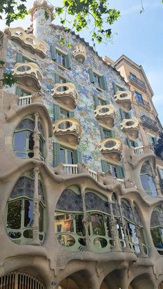 an ornate building with many windows and balconies on the side, in front of a tree