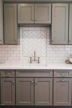 a kitchen with gray cabinets and white tile backsplash