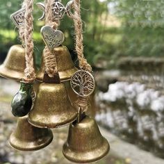 several bells hanging from strings in front of a stream and trees with hearts on them