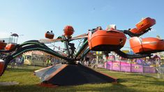 an orange and black carnival ride in the grass