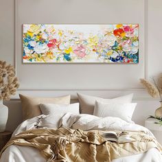 a large painting on the wall above a bed with white linens and pillows in front of it