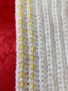 two different colored crocheted pieces of cloth next to each other on a red surface