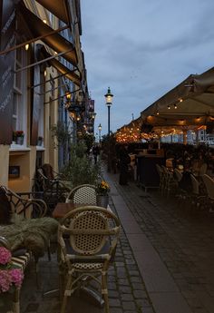 tables and chairs are lined up on the side of an alleyway at night time