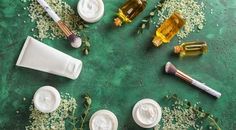 various beauty products are arranged on a green surface with flowers and leaves around them, including toothbrushes