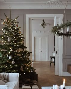 a living room with a christmas tree in the corner and candles on the coffee table