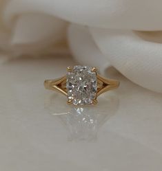 a diamond engagement ring sitting on top of a white cloth