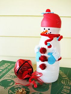 a snowman made out of plastic bottle sitting on top of a table next to a heart