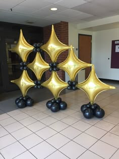 some black and gold balloons are in the middle of a room with tile flooring