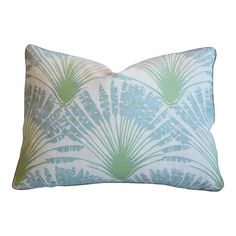 a blue and green pillow with palm leaves on it