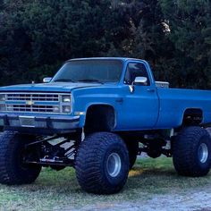 a large blue truck parked on top of a grass covered field