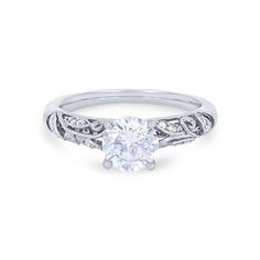 a white gold engagement ring with an oval cut diamond in the center and filigrees around the band