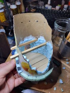 someone is making a model boat out of cardboard and glues it with wood sticks