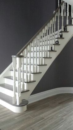 a white staircase with black walls and wood flooring in a room that is painted gray