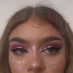 a close up of a woman with makeup on her face and stars all over her eyes