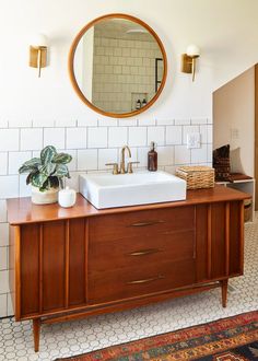 a bathroom vanity with two sinks and a large round mirror over it's top