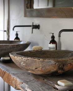 two wooden bowls sitting on top of a counter next to soap dispensers