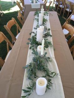 a long table is set with candles and greenery for an outdoor event or gathering