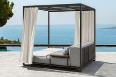 a canopy bed sitting on top of a patio next to the ocean