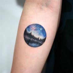 a person with a tattoo on their arm that has an image of the night sky