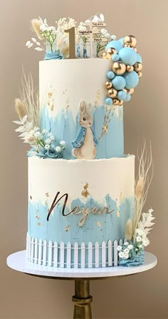 a three tiered cake with blue frosting and gold decorations