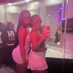 two women taking a selfie in front of a mirror