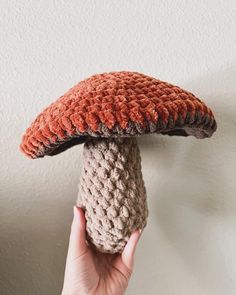 a hand holding up a crocheted mushroom