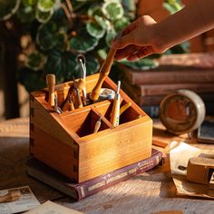 a wooden box filled with lots of pens and pencils on top of a table